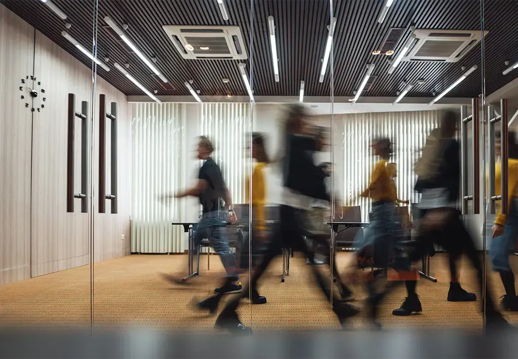 Blurred motion of professionals walking in a modern office with glass walls and contemporary lighting