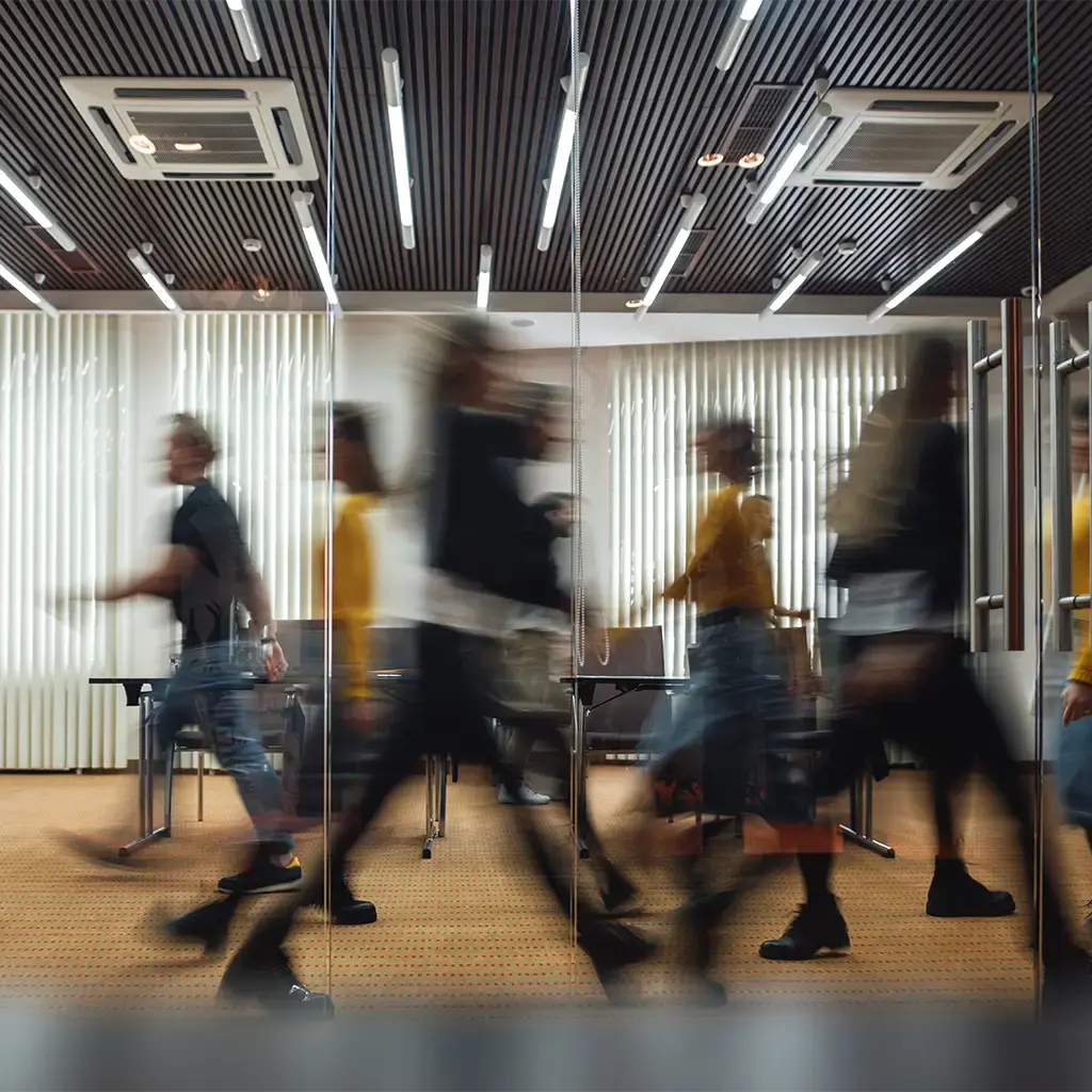 Blurred motion of professionals walking in a modern office with glass walls and contemporary lighting
