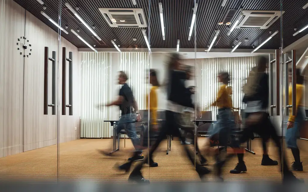 Blurred motion of professionals walking in a modern office with glass walls and contemporary lighting