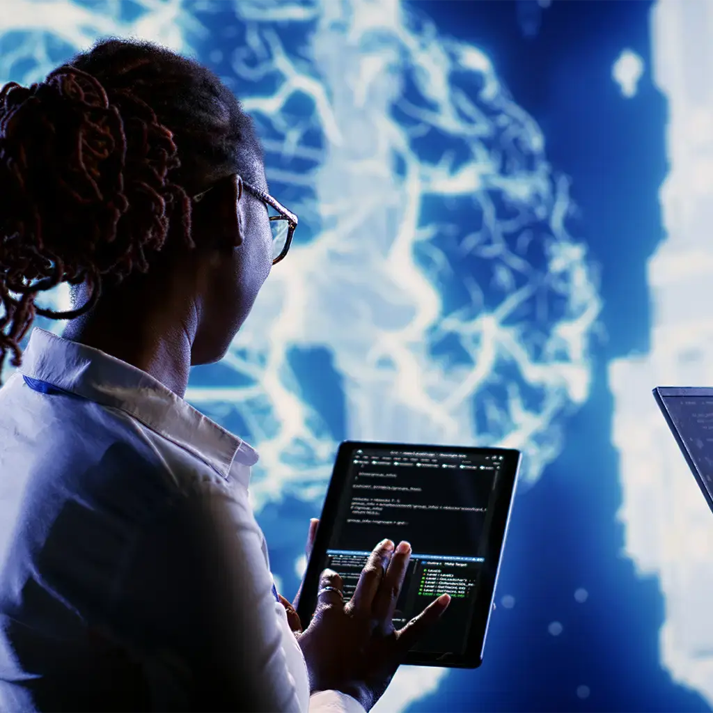 Developers coding with tablets and laptops in front of a glowing digital brain interface.