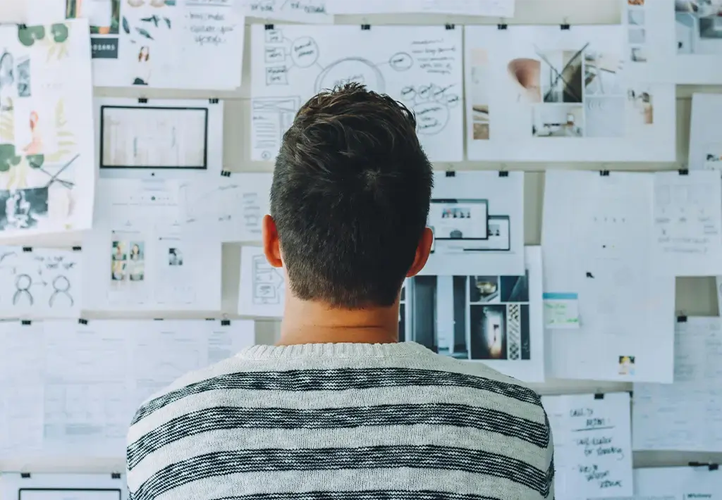 Consultant analyzing strategy on a wall in project sketches and dashboards