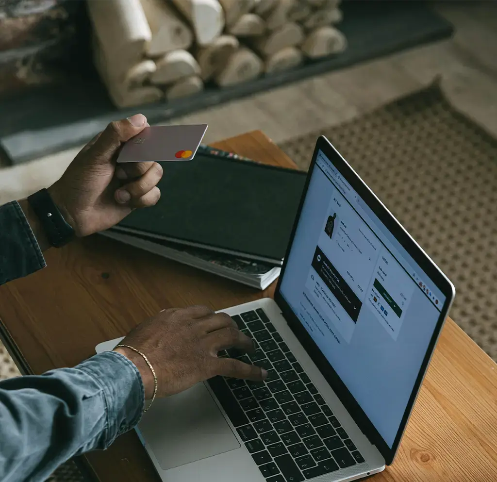 Person holding credit card and booking on their laptop