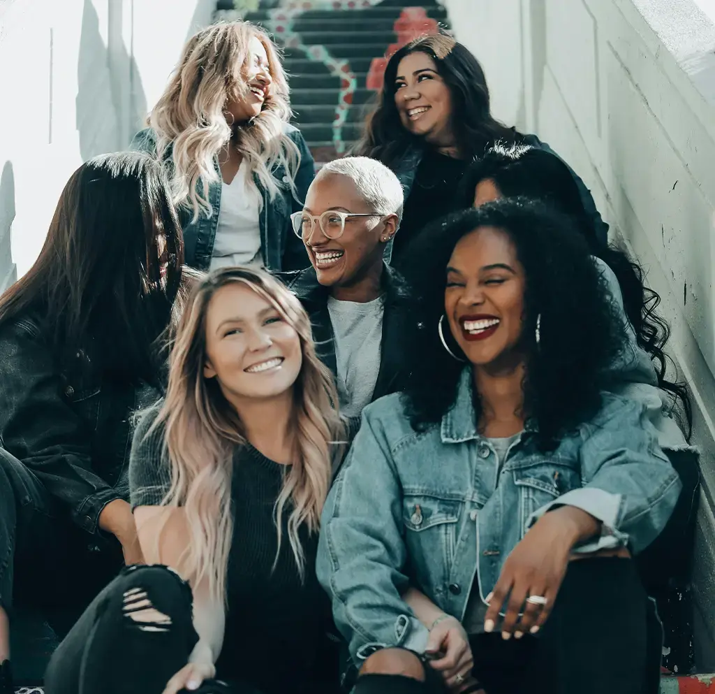 Group of people sitting on stairs, smiling and enjoying a casual team moment outdoors.