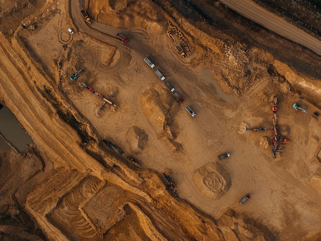 Aerial view of a large open-pit mining site with excavation machinery and trucks in operation.