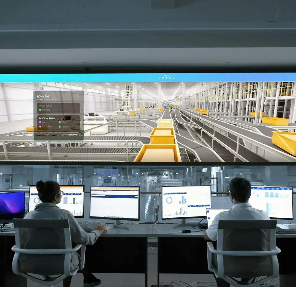 Technicians monitoring industrial automation data and systems on multiple screens in a smart factory control room.