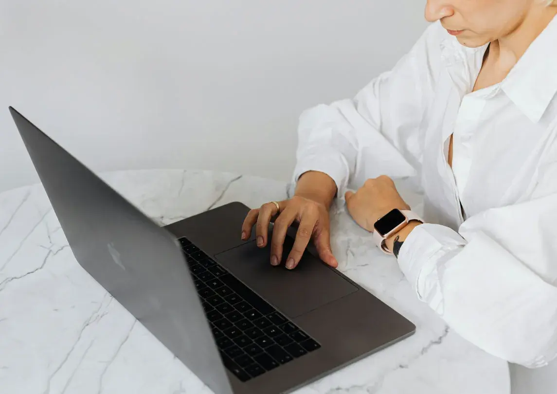 A person sitting at the table looking a laptop.