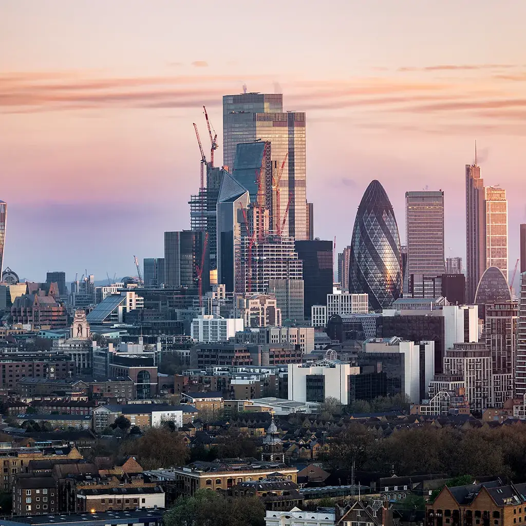 London skyline at sunset featuring modern financial district skyscrapers, including the Gherkin and Walkie Talkie.
