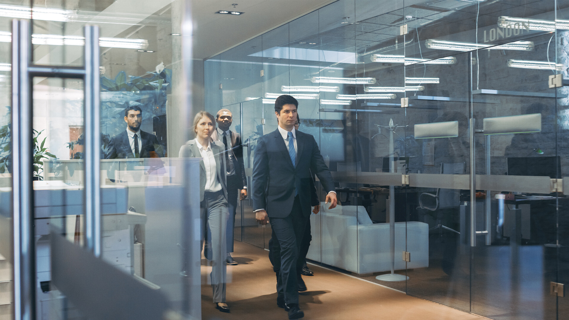 office-workers-walking-along-a-glazed-corridor-in-an-office-hero
