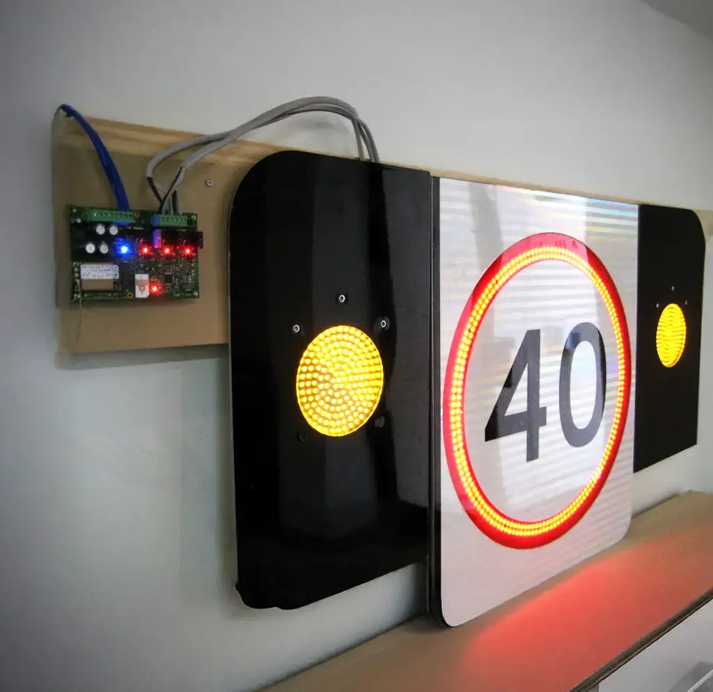 Electronic speed limit sign with 40 km/h display and warning lights connected to a smart traffic control board.