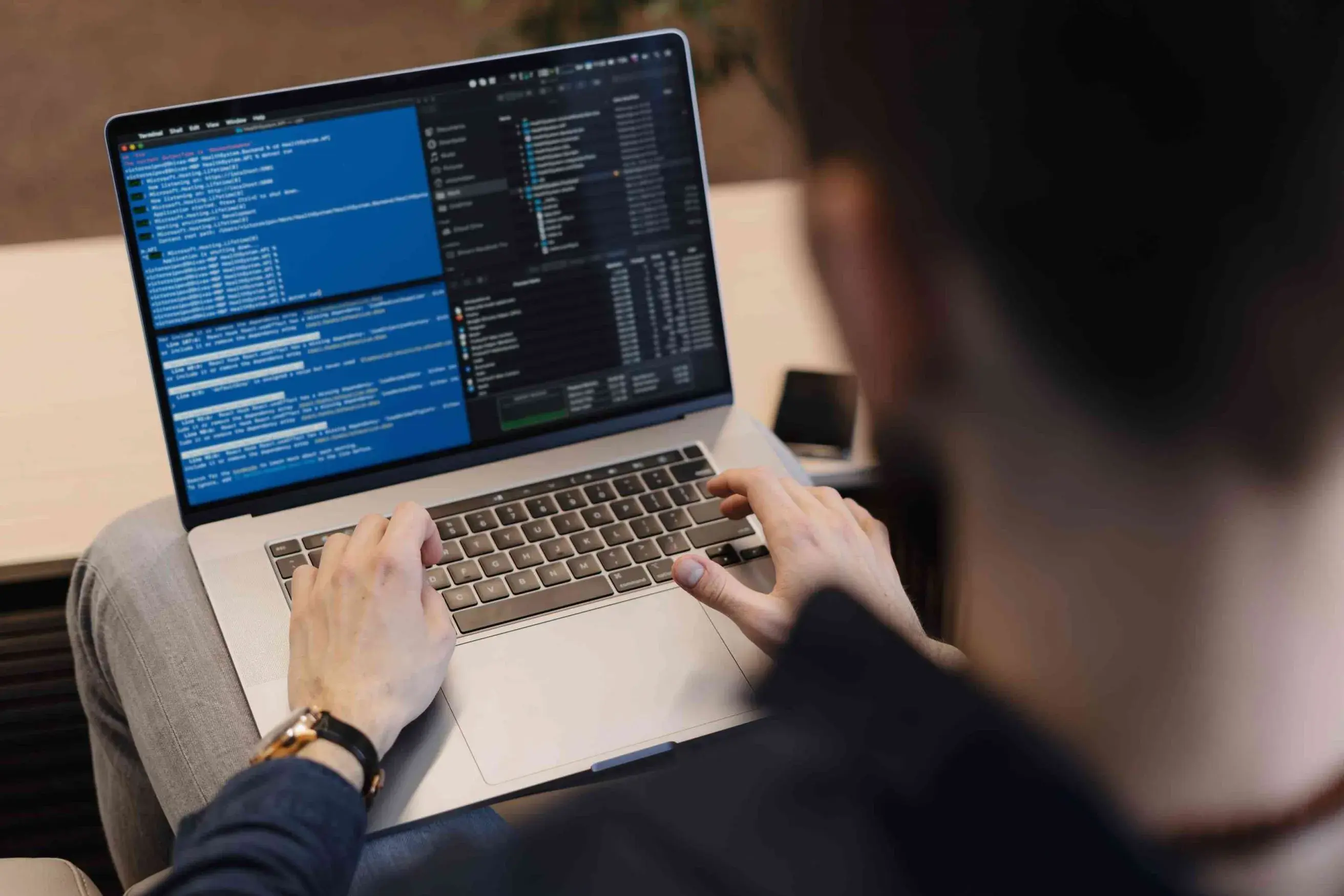 A person sitting at a desk with a laptop open, aiding a Creative Software Services Provider in achieving cloud-agnostic goals.