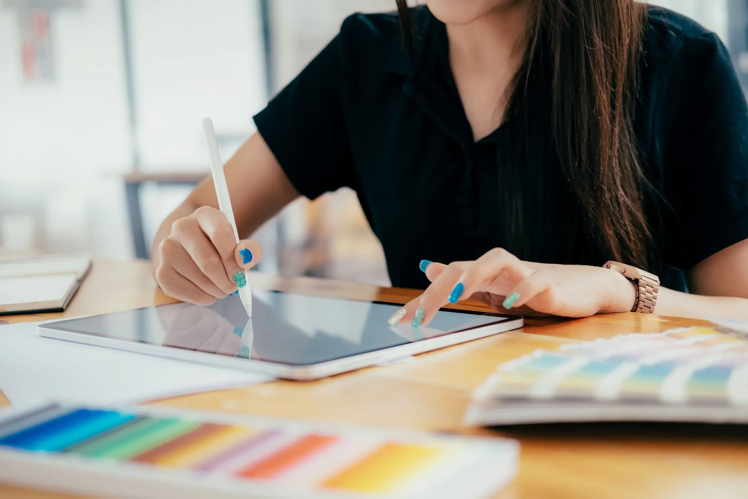 A woman working on a tablet with a pencil, aiding a creative software services provider in their journey to be cloud-agnostic.