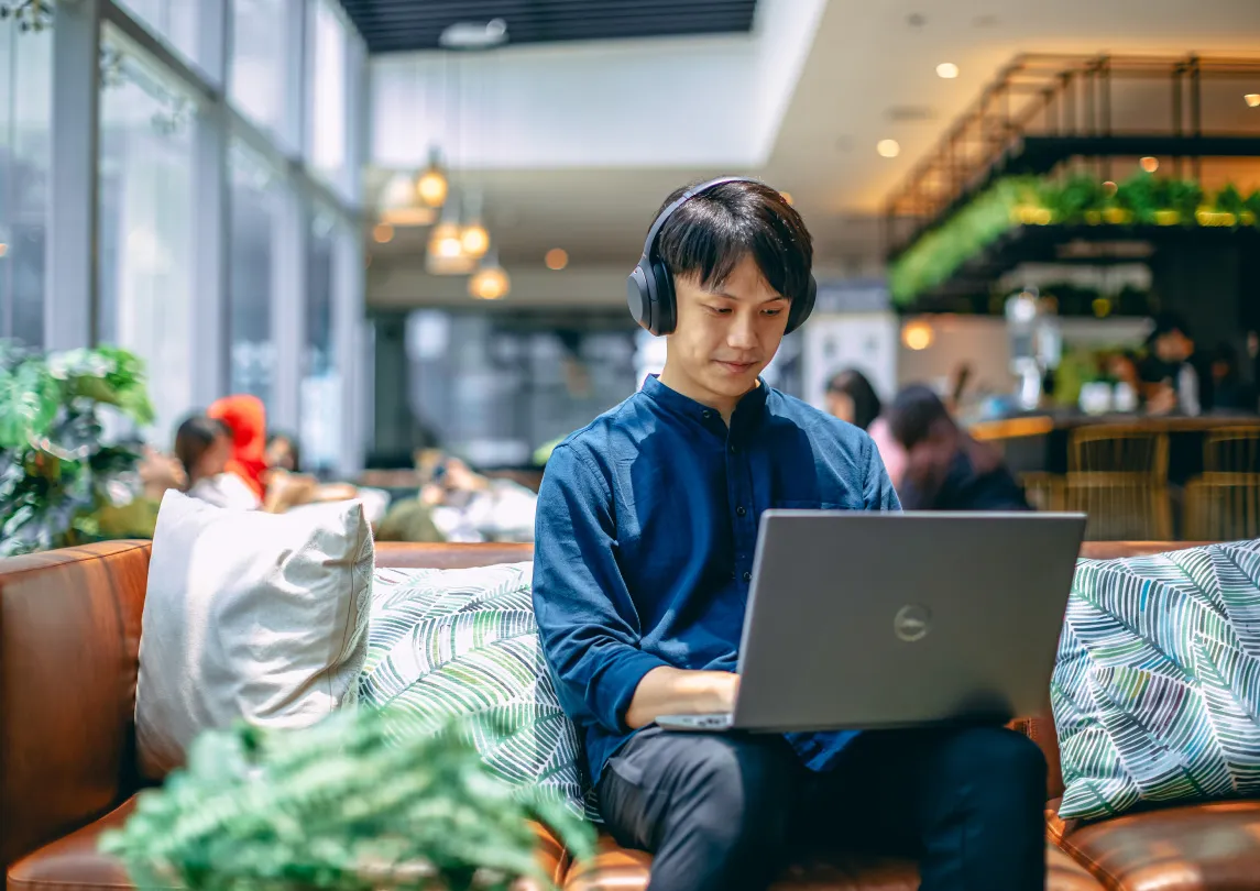 A man sitting on a couch working on a laptop
