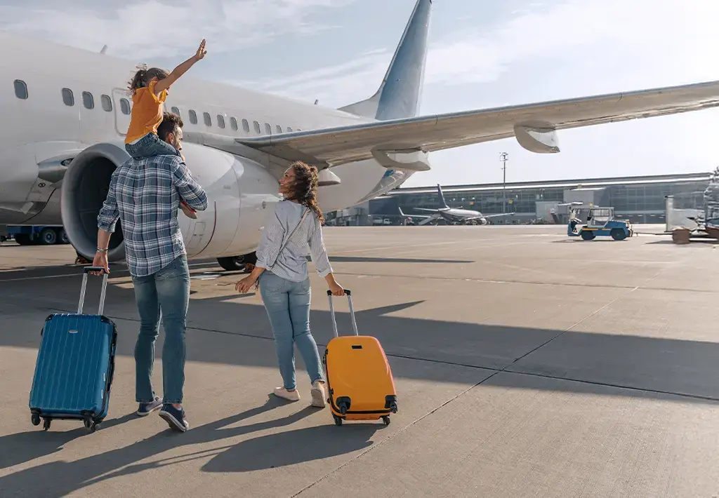 Travelers with luggage walking toward a commercial airplane, representing aviation and digital journey solutions.