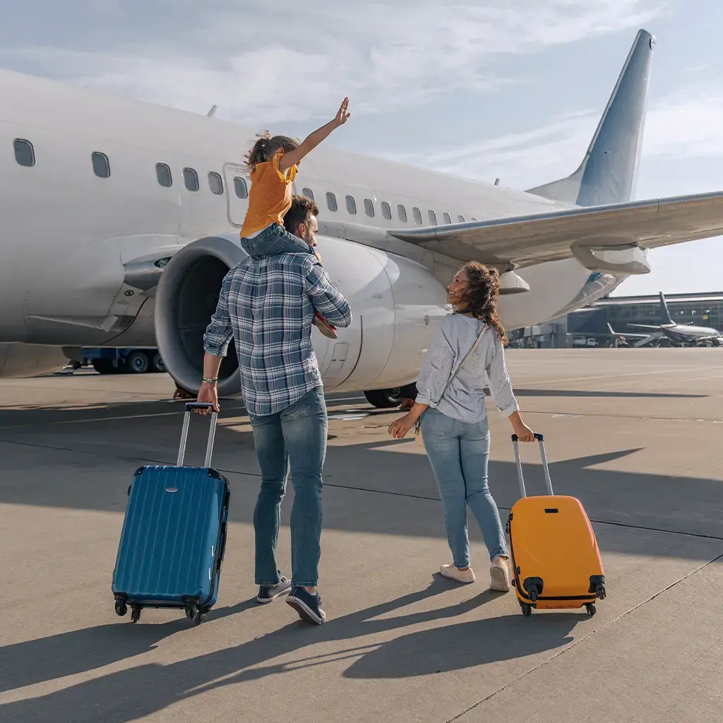Travelers with luggage walking toward a commercial airplane, representing aviation and digital journey solutions.
