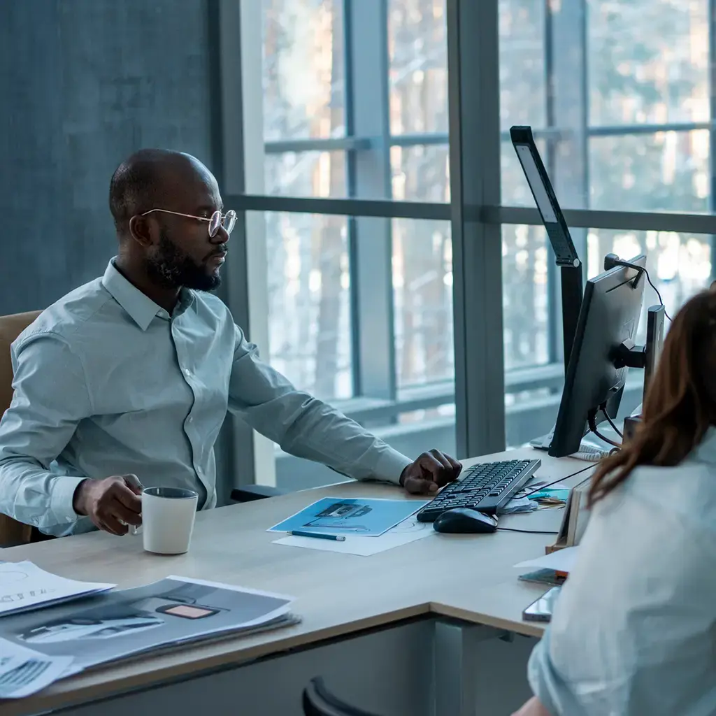 Team working at desks with design visuals and digital renderings on screen.