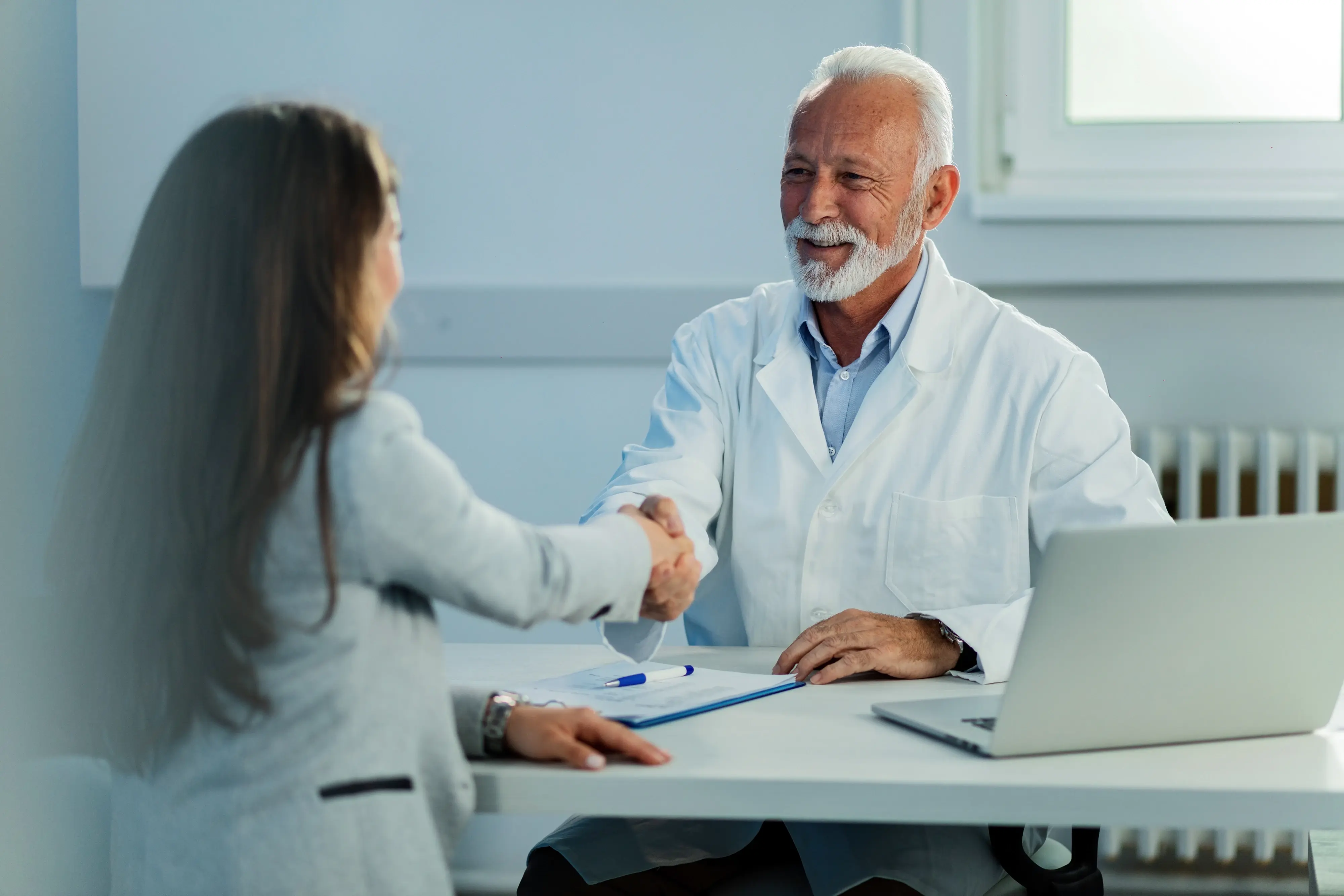 A doctor and patient shake hands, representing healthcare innovations that benefit people and profit.
