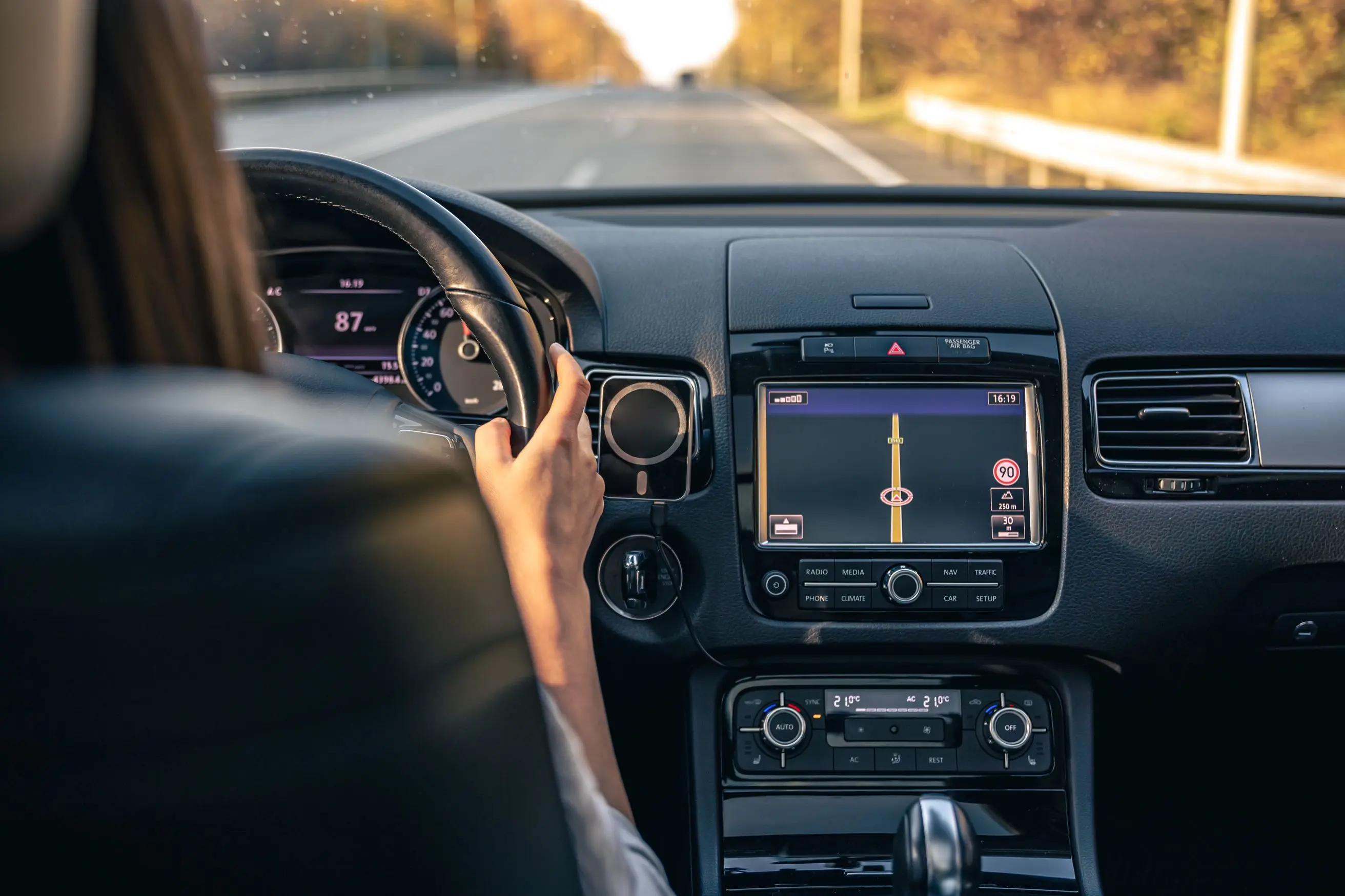 A woman driving a car with a GPS device, showcasing the future of automobile experiences driven by information engineering.