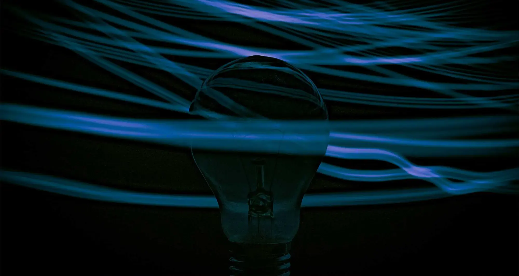 blue light streaks surrounding light bulb in the dark