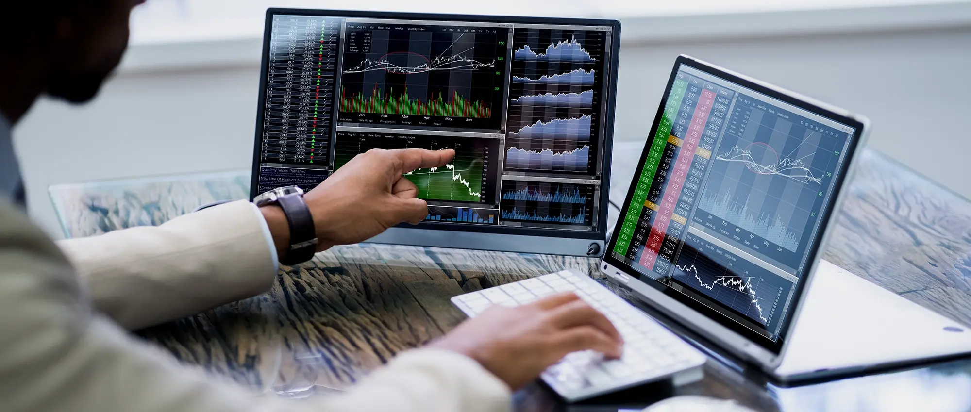 A man analyzes graphs on two computers, unlocking real-time insights for supply chain decision-making