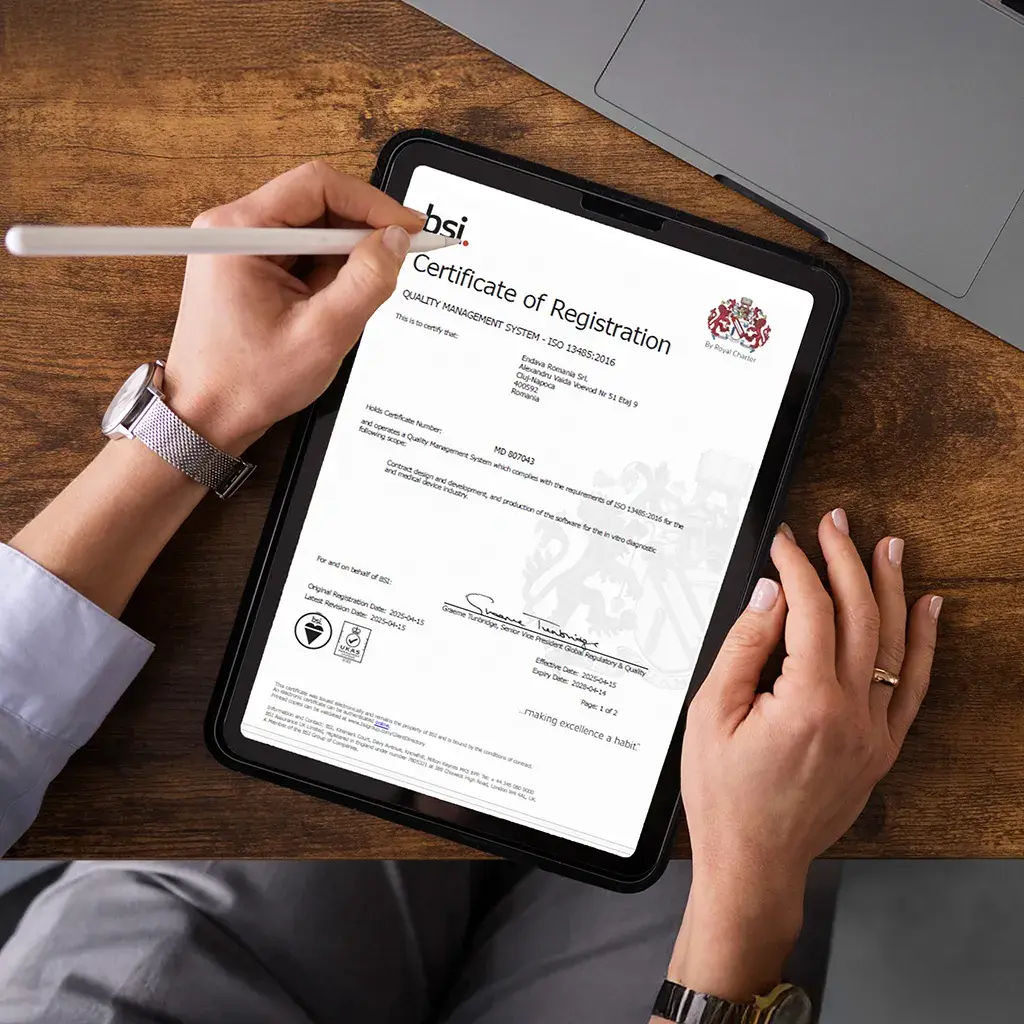 Hands holding a tablet displaying an ISO 13485:2016 quality certification for medical device development.