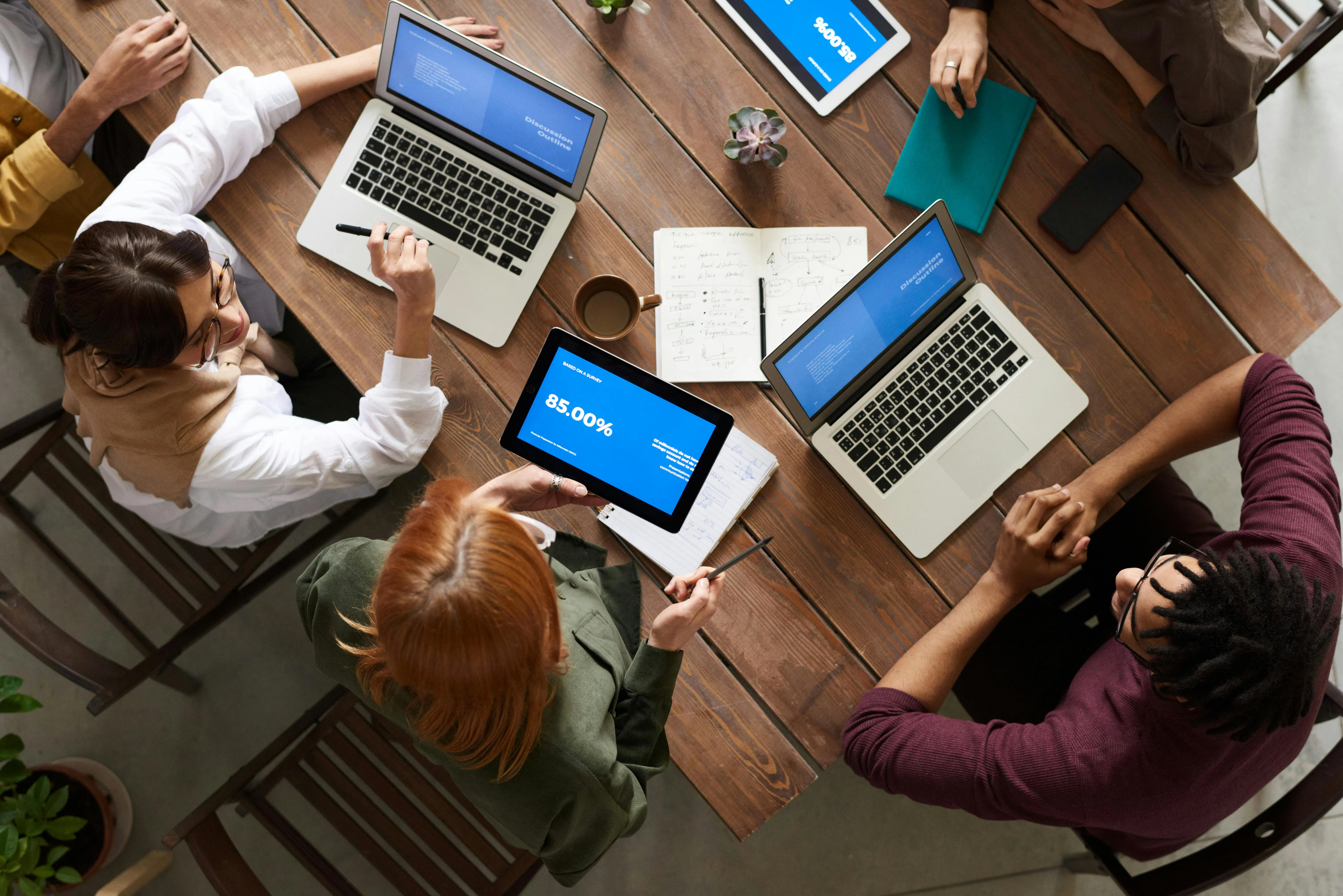 A group of people sitting at the table working on laptops