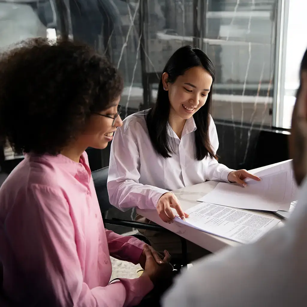 Team members in a business meeting reviewing printed documents together in a modern office.