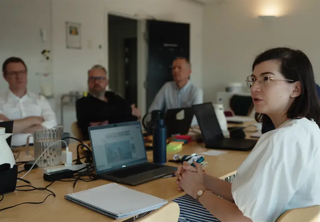Team collaborating in a meeting room with laptops and notepads on the table
