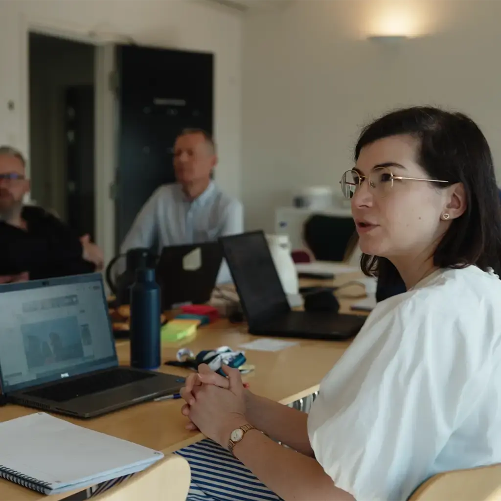 Team collaborating in a meeting room with laptops and notepads on the table