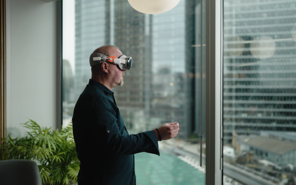 Professional using augmented reality headset in modern office overlooking urban cityscape.
