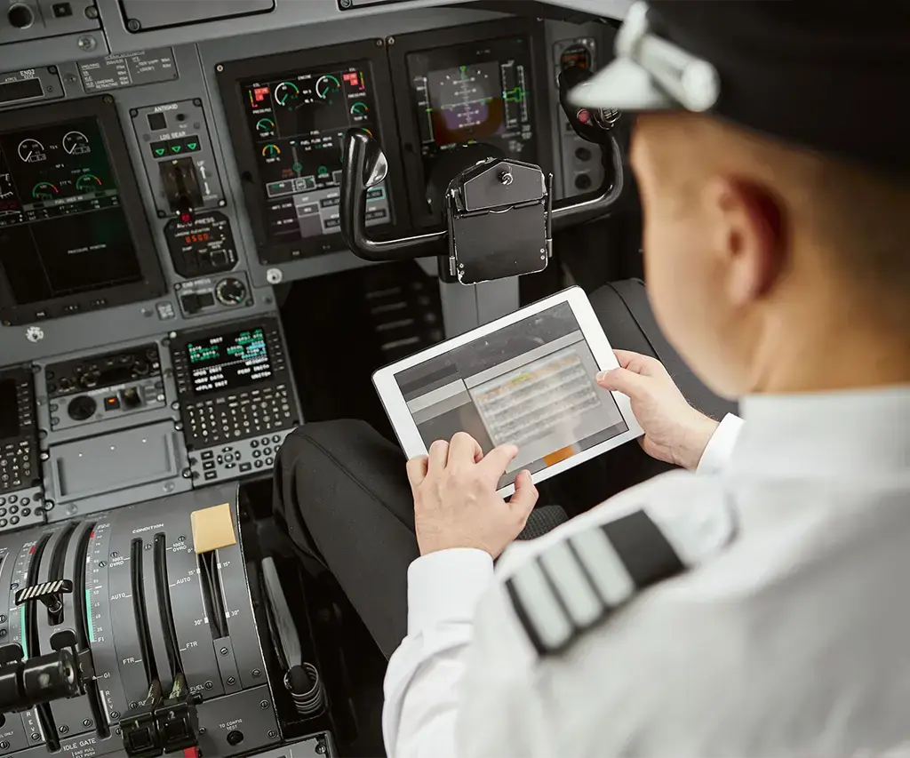 Pilot using a tablet device in an aircraft cockpit for digital flight operations.