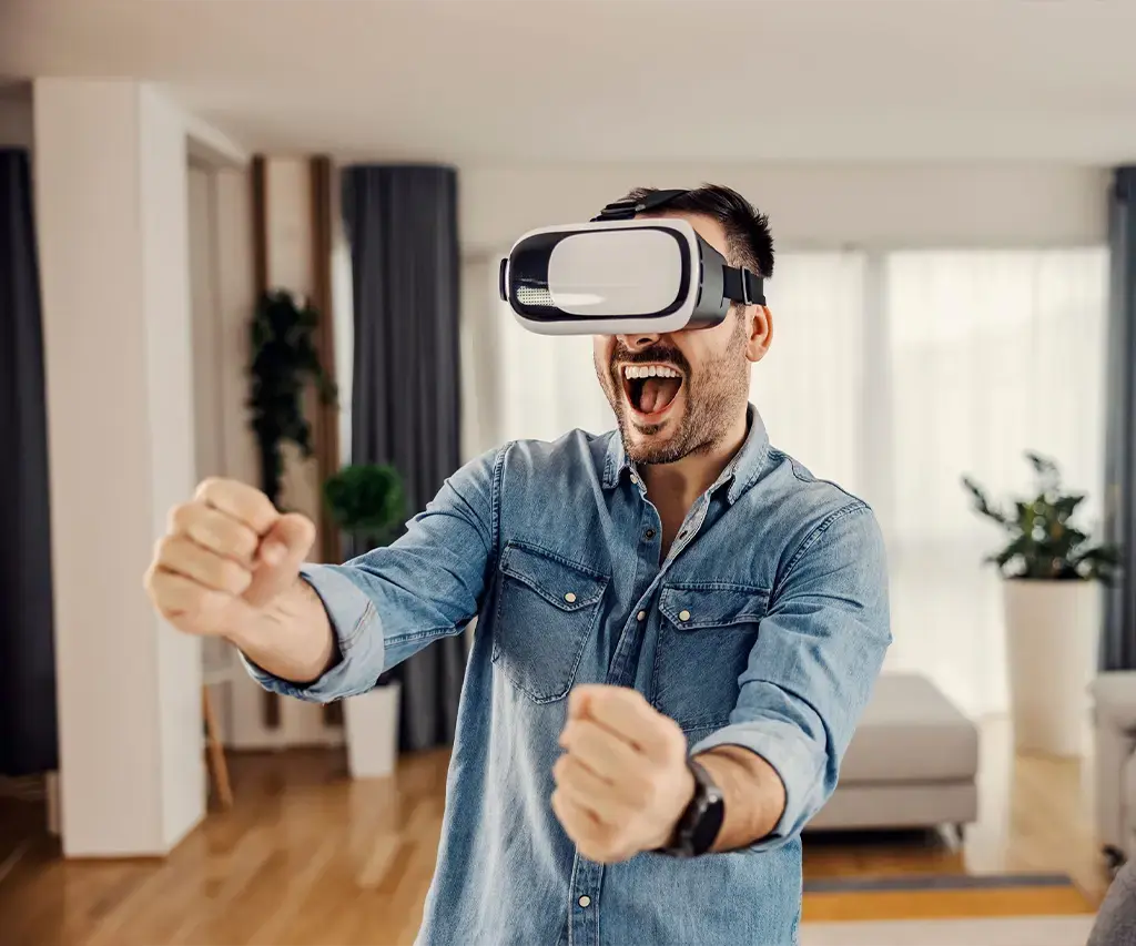 Person using a VR headset at home, appearing excited and engaged in virtual interaction.