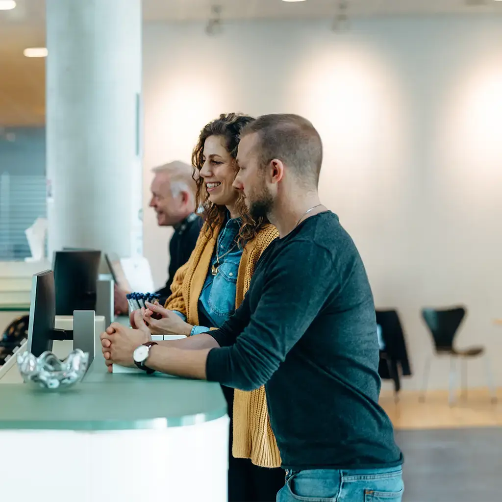 A mixed group of welcoming colleagues speak to each other over a counter with computers
